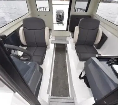 Interior view of a modern boat with two grey seats, a steering wheel, and an engine visible through the back window.